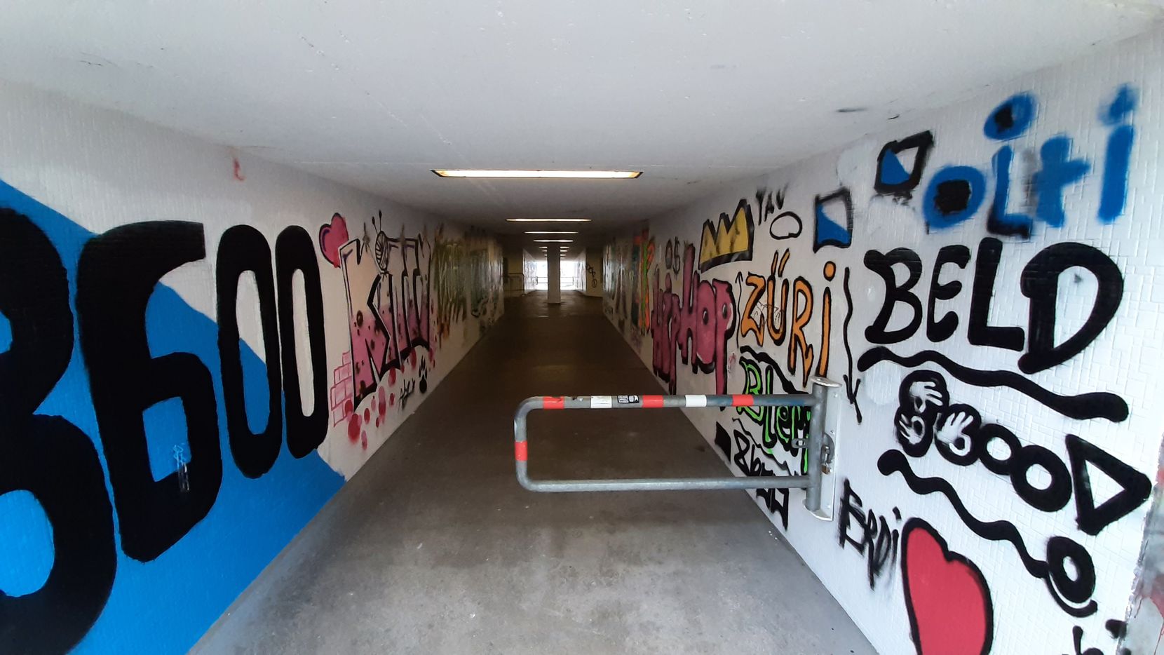 Graffiti und Tags in einer dunklen Unterführung.